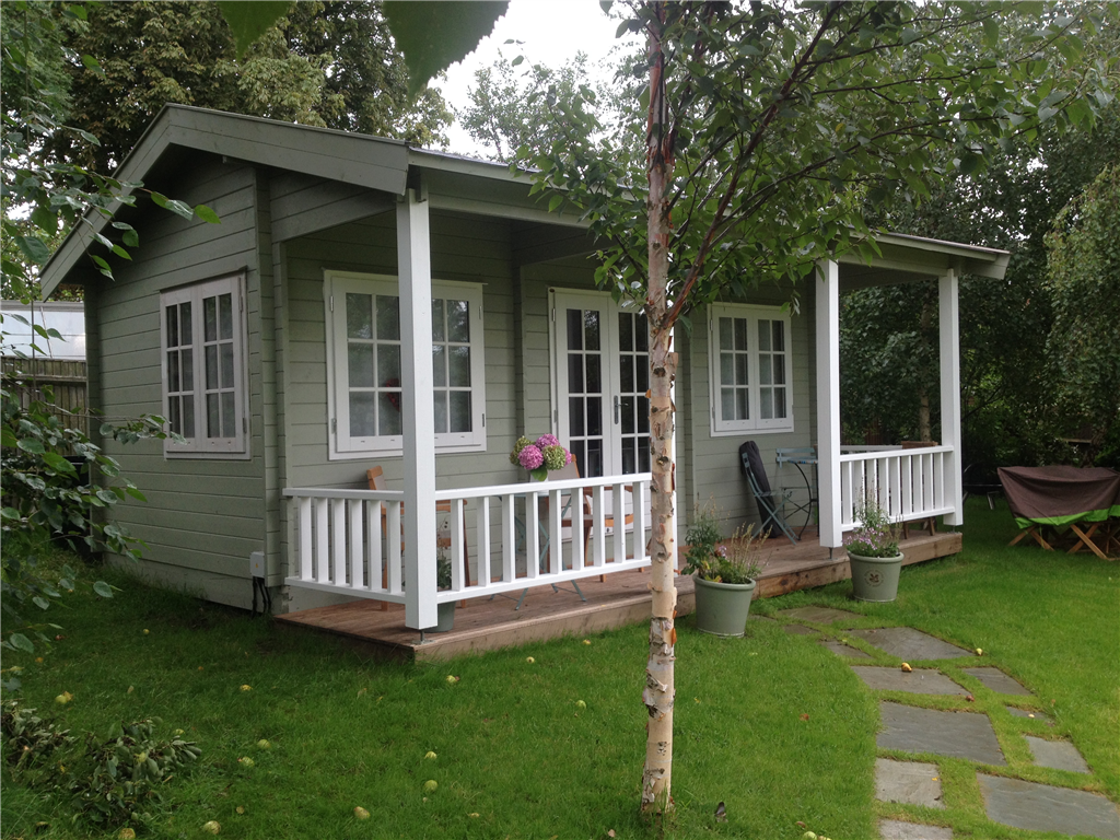 Traditional garden log cabin, cricket pavilion style, with veranda and balustrades.  Custom designs available. Gallery Image