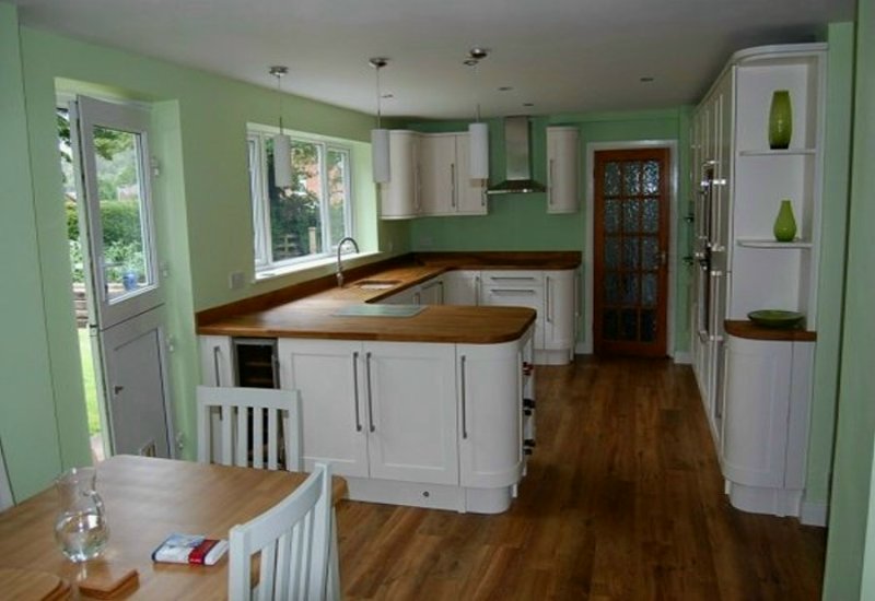 Bespoke Ivory Shaker style kitchen with curved doors and Oak worktops. Instant boiling water tap with inset sink. Integrated appliances including wine cooler and tall oven. Gallery Image